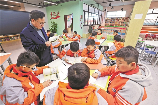 图为近日在嘉兴市南湖区余新镇中心小学图书馆的“老少阅读攀登合作社图书漂流站”，退休教师陶坤华与孩子们一起阅读。